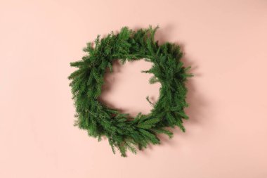 Pembe arka planda köknar dallarından yapılmış Noel çelengi