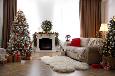 Noel ağaçları ve şöminesi olan şenlikli bir salon.