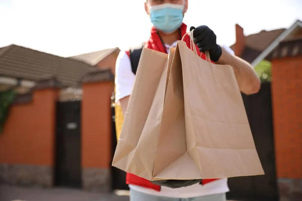 stock image Courier in protective mask and gloves with order outdoors, closeup. Restaurant delivery service during coronavirus quarantine