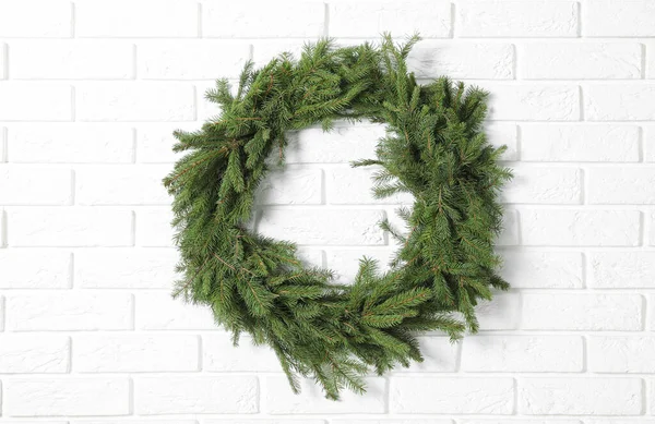 Beyaz tuğla duvardaki köknar dallarından yapılmış Noel çelengi