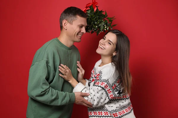 Couple Heureux Debout Sous Bouquet Gui Sur Fond Rouge — Photo