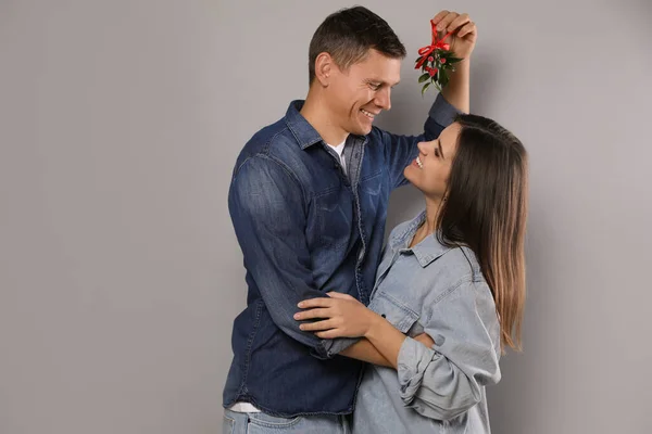 Happy Couple Standing Mistletoe Bunch Grey Background — Stock Photo, Image