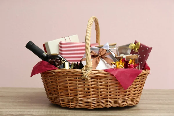 Wicker gift basket with bottle of wine on wooden table