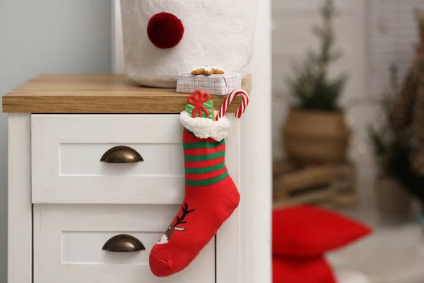 Stocking with presents hanging on drawer in children\'s room, space for text. Saint Nicholas Day tradition