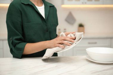 Kadın mutfakta havluyla tabağı siliyor, yakın plan.