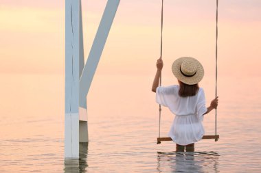 Suyun üzerinde güneşin doğuşunu seyreden genç bir kadın.