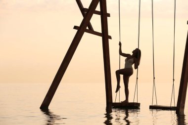 Suyun üzerinde güneşin doğuşunu seyreden genç bir kadın.