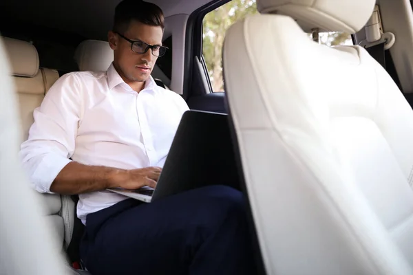 Modern Arabanın Arka Koltuğunda Dizüstü Bilgisayarla Çalışan Yakışıklı Bir Adam — Stok fotoğraf