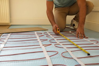 Profesyonel işçi elektrikli ısıtma sistemini kapalı bir yere kuruyor, kapatıyor.
