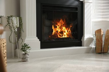 Parlak oturma odasının içinde yapay şömine ve sepetin içinde odun var.