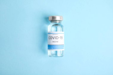 Vial with coronavirus vaccine on light blue background, top view clipart