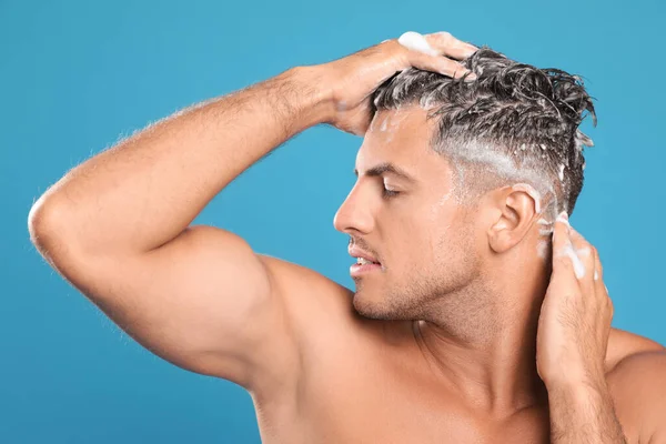 Yakışıklı Adam Açık Mavi Arka Planda Saç Yıkıyor — Stok fotoğraf