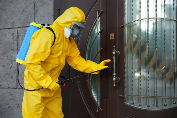 Persona Traje Materiales Peligrosos Desinfectando Puerta Entrada Con Rociador Tratamiento —  Fotos de Stock