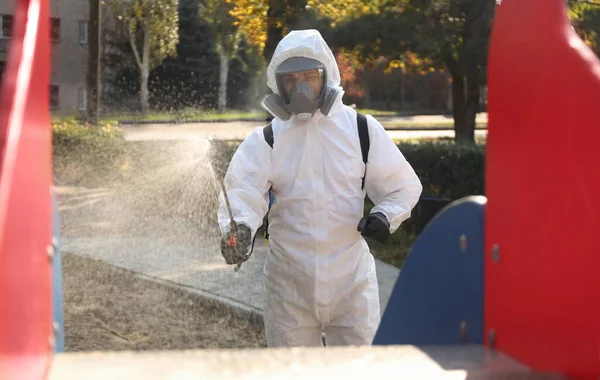 Hombre Con Traje Materiales Peligrosos Rociando Desinfectante Sobre Tobogán Parque —  Fotos de Stock