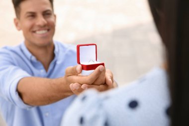 Nişan yüzüklü bir adam kız arkadaşına dışarıda evlenme teklif ediyor.