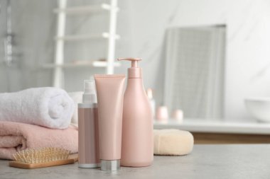 Tuvalette farklı saç bakım ürünleri, havlular ve fırçalar.