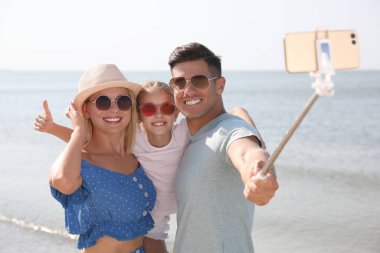 Mutlu aile güneşli bir günde sahilde selfie çekiyor.