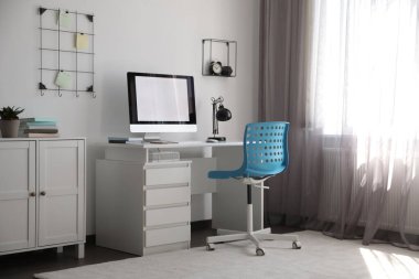 Masanın yanındaki rahat mavi sandalye şık bir ofis içinde.