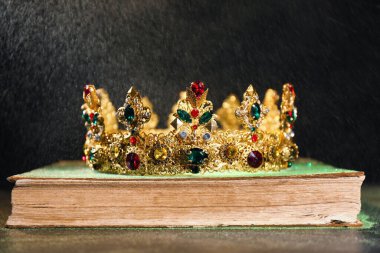 Siyah arka plana karşı eski kitaptaki güzel altın taç. Fantezi ögesi