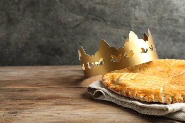 Geleneksel galette des Rois ve tahta masa üzerinde kağıt taç. Metin için boşluk