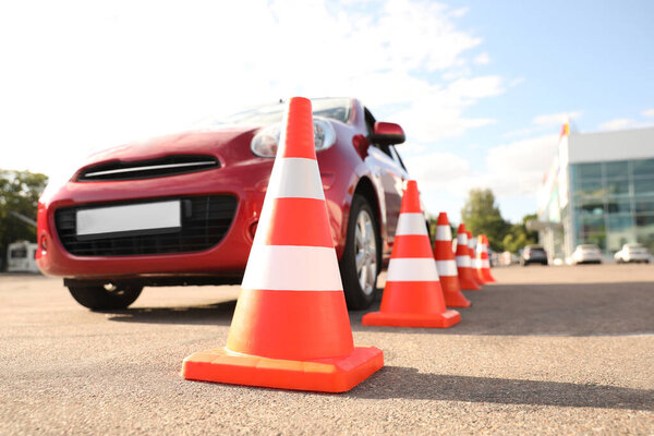 Traffic cones near red car outdoors. Driving school exam