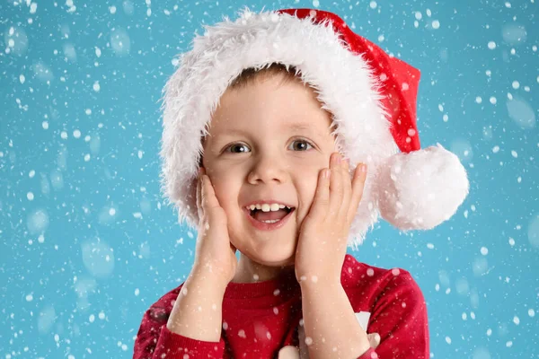 明るい青の背景に雪の下でサンタの帽子のかわいい子供 クリスマスのお祝い — ストック写真