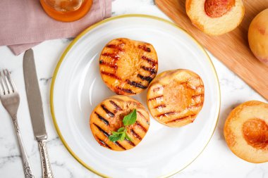 Lezzetli ızgara şeftali, beyaz mermer masa üzerinde nane, düz yatıyordu.