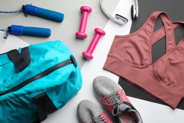 Spor çantalı düz kompozisyon ve açık gri arka planda spor giyim.