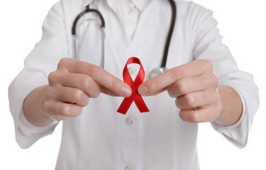 Doktor beyaz arka planda kırmızı kurdele tutuyor, yakın plan. AIDS Farkındalık Ayı