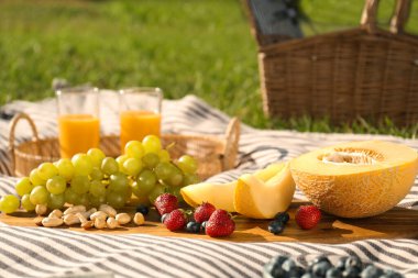 Açık yeşil çimlerde lezzetli yiyecek ve meyve suyu olan piknik battaniyesi.