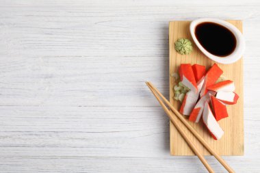 Beyaz ahşap masada servis edilen soya soslu taze yengeç çubukları. Metin için boşluk