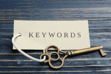 Mavi ahşap arka planda KEYWORDS etiketli anahtar, kapat