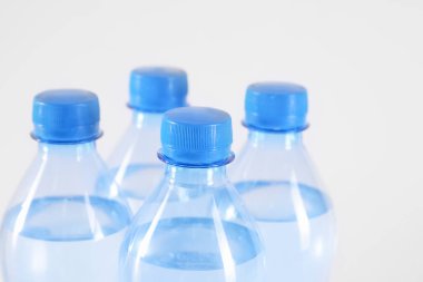Beyaz arka planda saf su bulunan plastik şişeler, yakın plan.