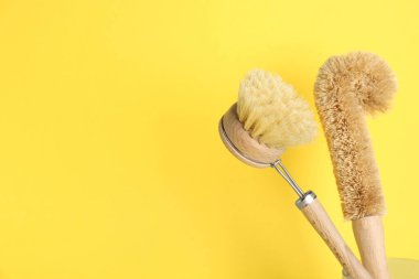 Sarı arkaplanda temizlik fırçaları, mesaj için boşluk. Bulaşık malzemeleri.