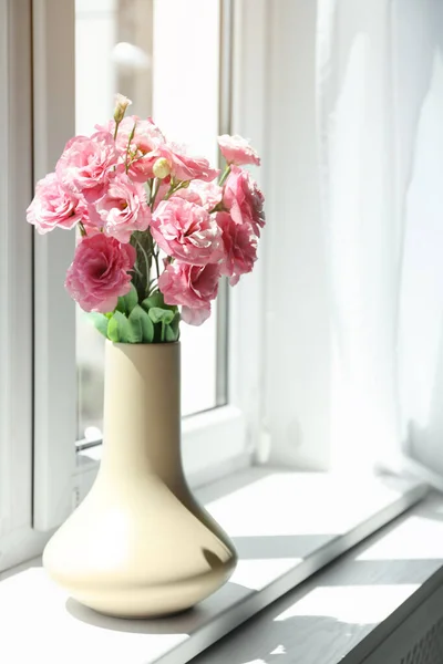 White vase with beautiful flowers on window sill in room