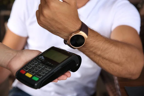 Man making payment with smart watch outdoors, closeup