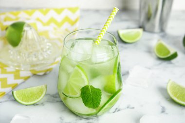 Lezzetli mojito ve beyaz mermer masadaki malzemeler.