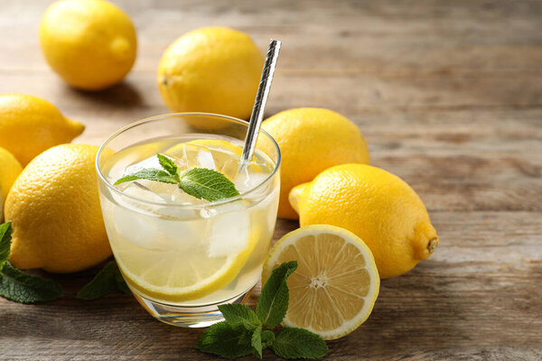 Натуральный лимонад с мятой и свежими фруктами на деревянном столе, крупный план. Летний освежающий напиток