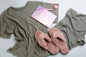 Pár načechraných pantoflí, pyžamo a zápisník na šedém pozadí, ploché ležely. Pohodlné domácí oblečení