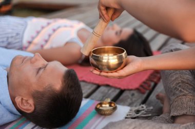Couple at healing session with singing bowl outdoors clipart