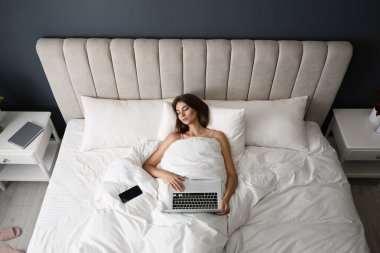 Dizüstü bilgisayarı ve akıllı telefonu olan yorgun bir kadın evde uyuyor.