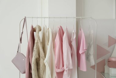 Soyunma odasındaki beyaz duvarın yanında şık kıyafetlerle dizilin.