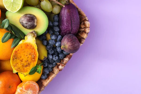 Assortment of fresh exotic fruits on lilac background, top view. Space for text