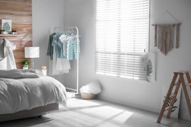 Elbise askılığı ve geniş pencereli şık bir yatak odası.