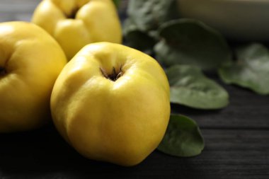 Siyah ahşap masa üzerinde yaprakları olan taze, organik ayvalar.