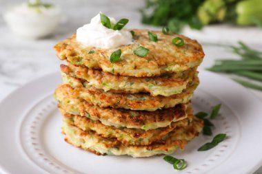 Lezzetli kabaklı börek, ekşi krema ve tabakta yeşil soğan, yakın plan.