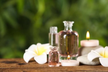 Ahşap masa üzerinde aroma yağı ve çiçeklerle güzel bir spa kompozisyonu, yakın plan.