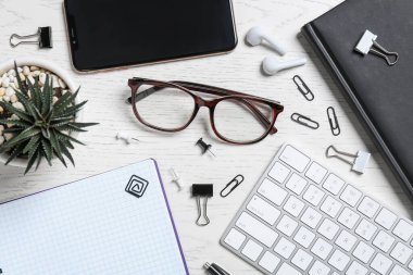 Düz kompozisyon, ofis eşyaları ve gözlüklerle ahşap masada yatıyordu.