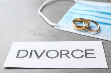 Koruyucu maskeli kompozisyon ve gri masada alyanslar. Koronavirüs karantinası sırasında boşan