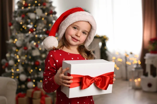 かわいい女の子保持ギフトボックスで部屋に飾られたクリスマスのために — ストック写真